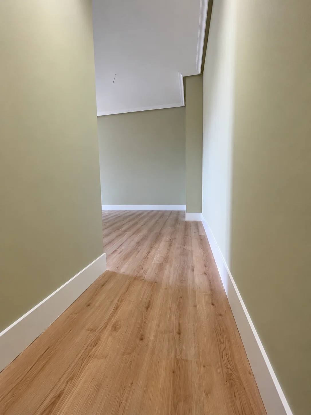 Suelo laminado color roble con rodapié blanco de 15 cm en una obra terminada